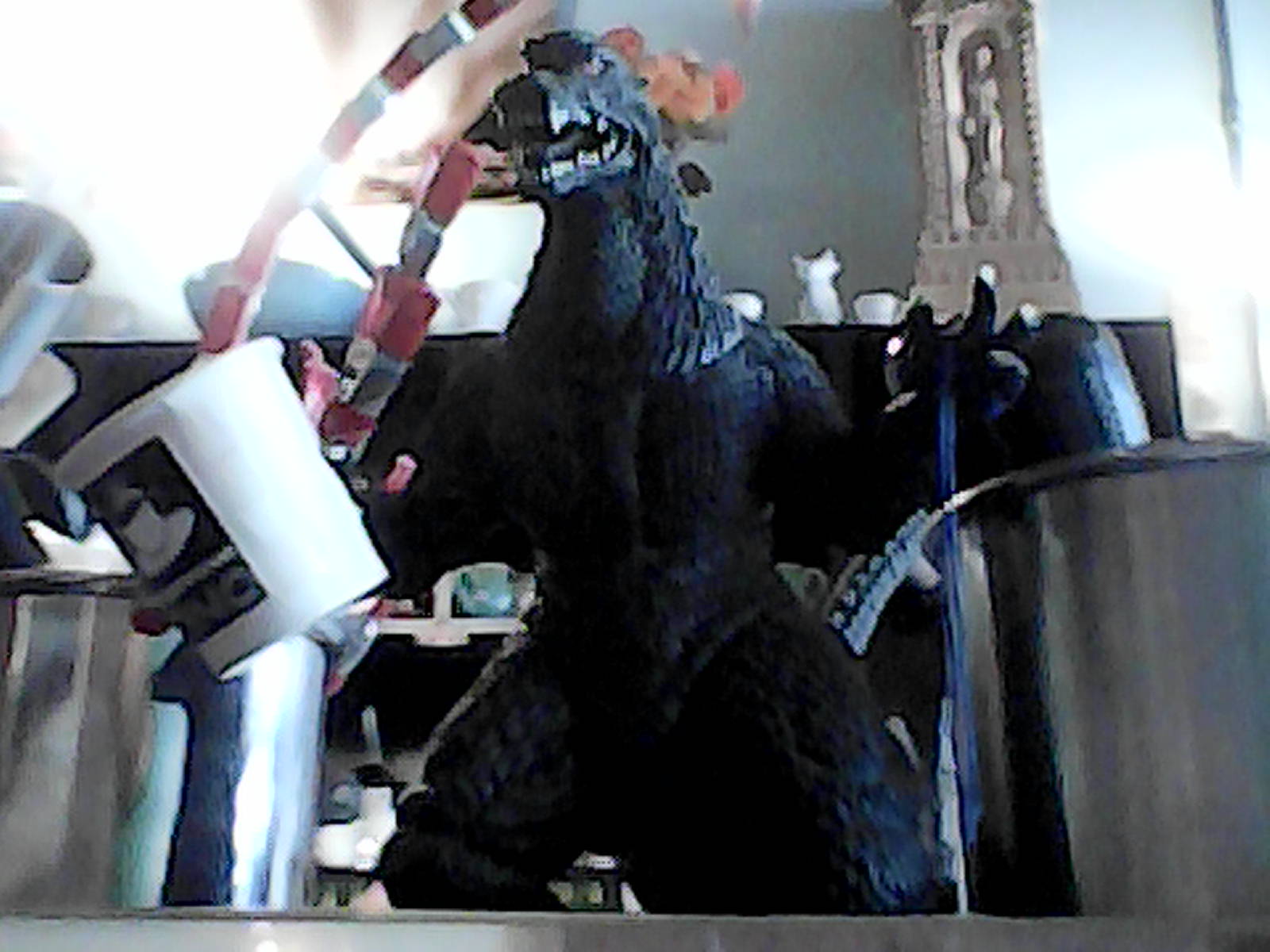 Godzilla toy holds mini coffee mug.